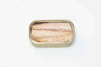 A photorealistic close-up of a white tray containing three PYSCIS cans labeled "3-Pack Little Bullet Tuna Filets" (SKU: AUX22). The label features the PYSCIS brand logo and highlights the product's use of sustainable fishing practices. A blue and green gradient adorns the label in the background.  The image focuses on a single can tilted slightly forward, revealing a glimpse of the flaky, white tuna meat bathed in olive oil through the transparent window in the can.