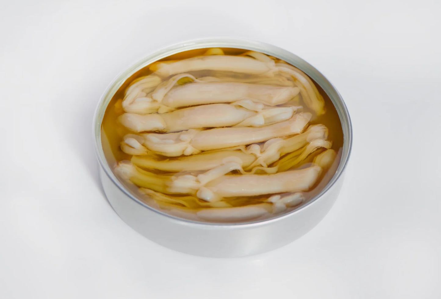 A close-up image of an open tin of razor clams. The tin is positioned on a white background, revealing its contents. Inside the tin, several plump razor clams are arranged neatly, their shells slightly ajar, showcasing their delicate white meat. The clams are bathed in a clear, shimmering liquid, their natural olive oil. The tin is labeled with a blue and white sticker bearing the brand name "PYSCIS" and the product name "Razor Clams in Olive Oil."